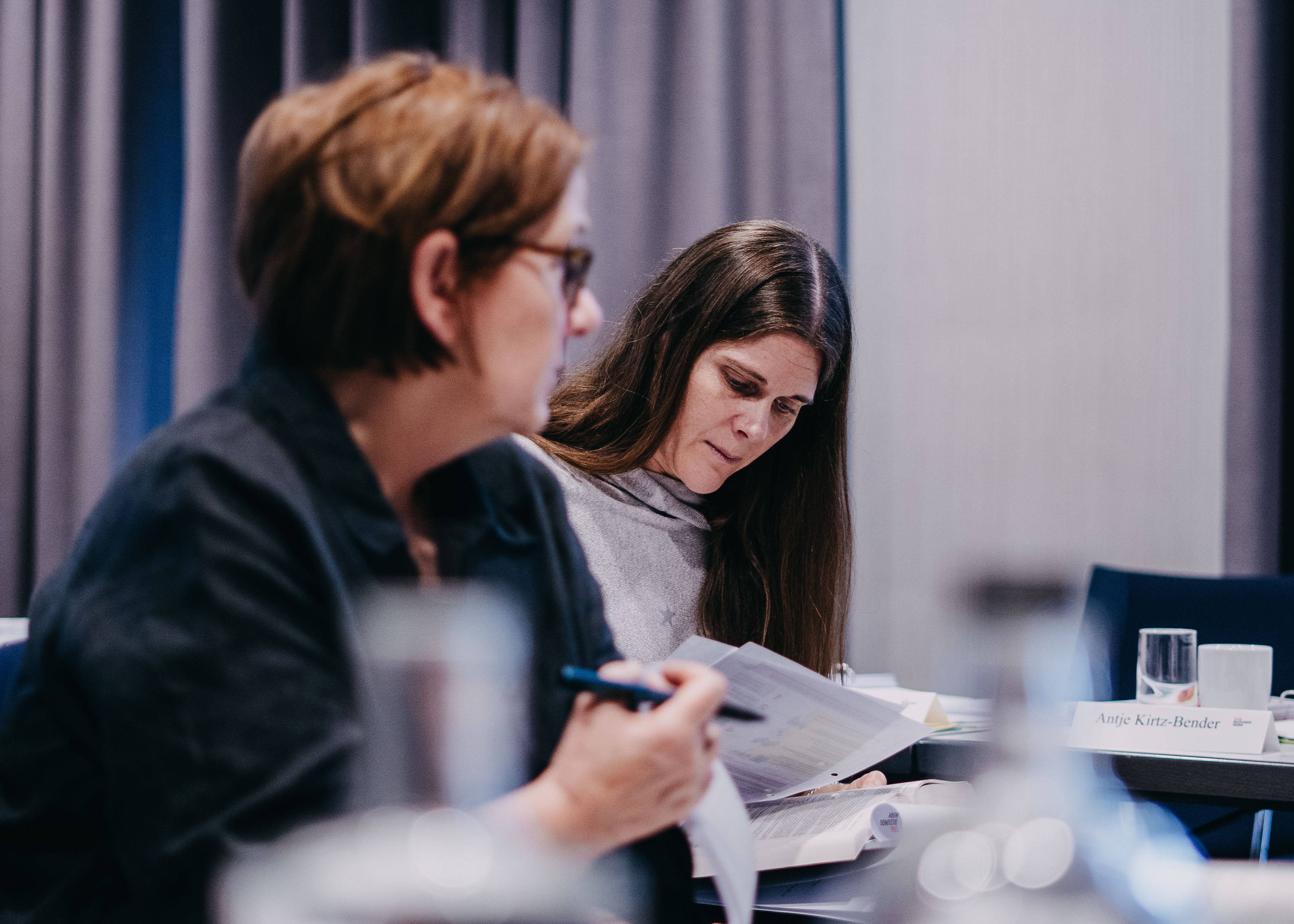 Zwei Teilnehmende einer Wahlvorstandsschulung machen sich Notizen und hören aufmerksam zu.