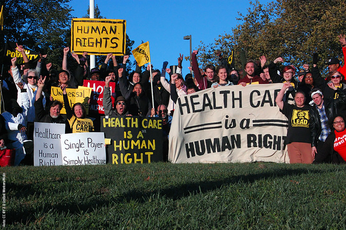 Demonstrant_innen mit Plakaten und Bannern zum Thema Gesundheit und Pflege als Menschenrecht.