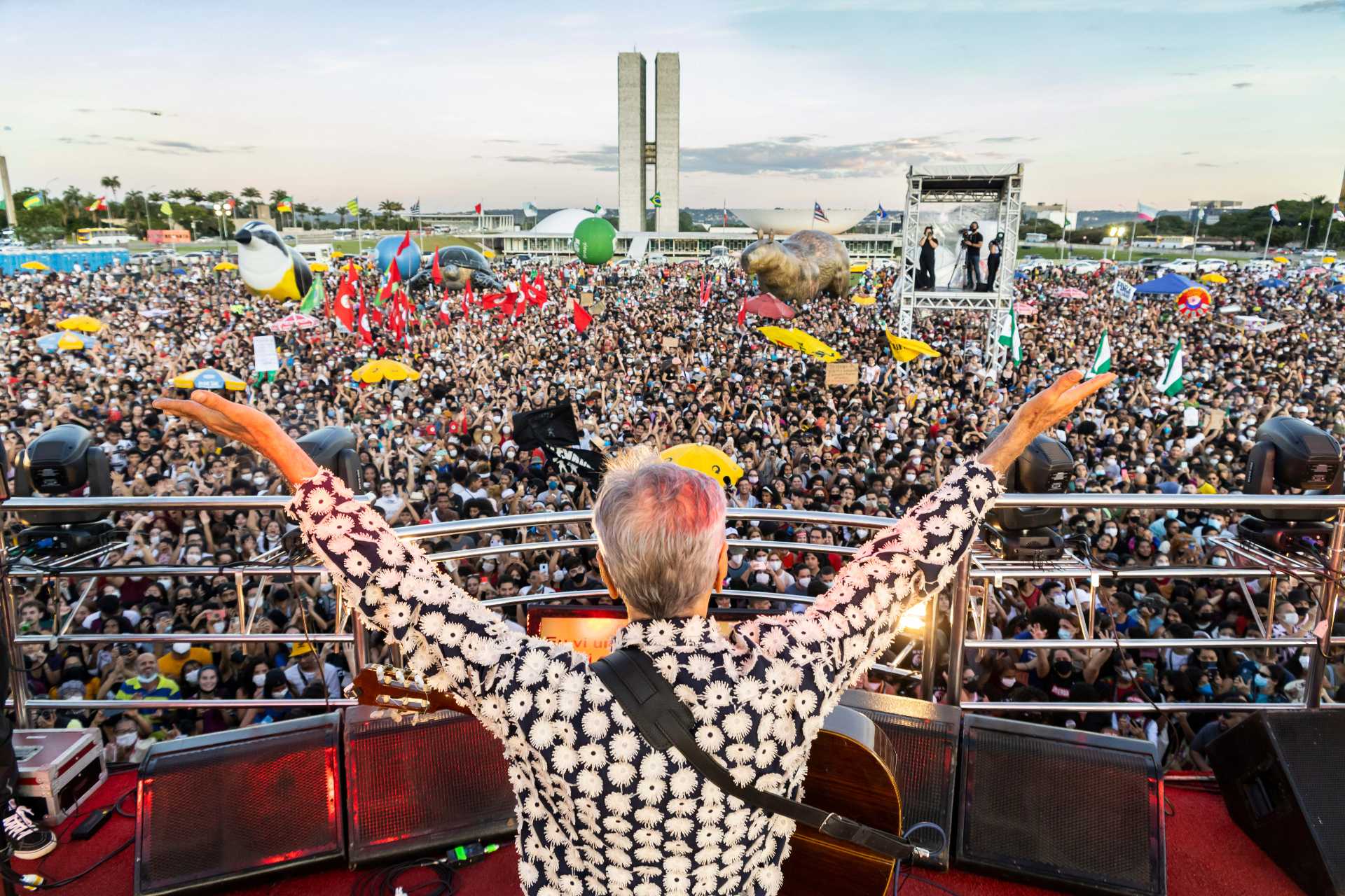 Künstlern Caetano Veloso von hinten und vor einer Masse von Demonstrant_innen in Brasilia.