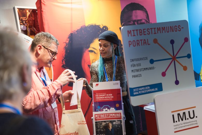 Ein Mann und eine Frau unterhalten sich am bunten Infostand