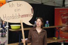 Frau hät ein Schild hoch auf dem steht: Ich bin ein Handelshemniss.