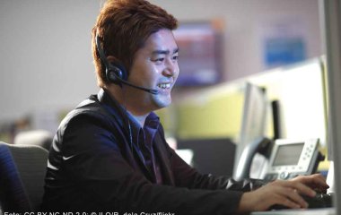 Arbeitnehmer*in mit Headset am Computer.