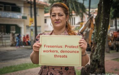 Fresenius-Mitarbeiterin hält ein Schild vor der Brust mit der Aufschrift: Fresenius Protect workers, denounce threats 