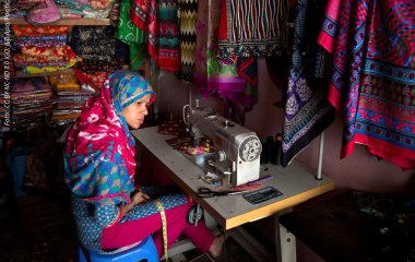 Näherin sitzt an einer Nähmaschine.