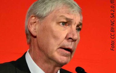 Foto von Michael Sommer vorm Mikrofon mit rotem Hintergrund.